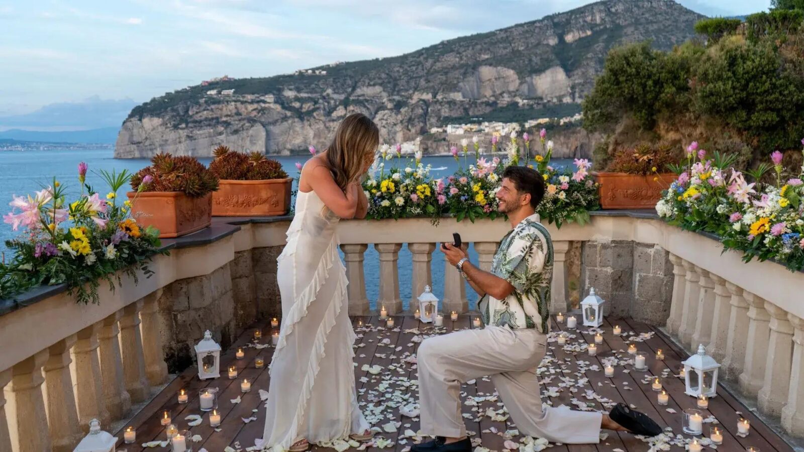 Couple during a romantic marriage proposal on a panoramic terrace in Ischia overlooking the sea at sunset